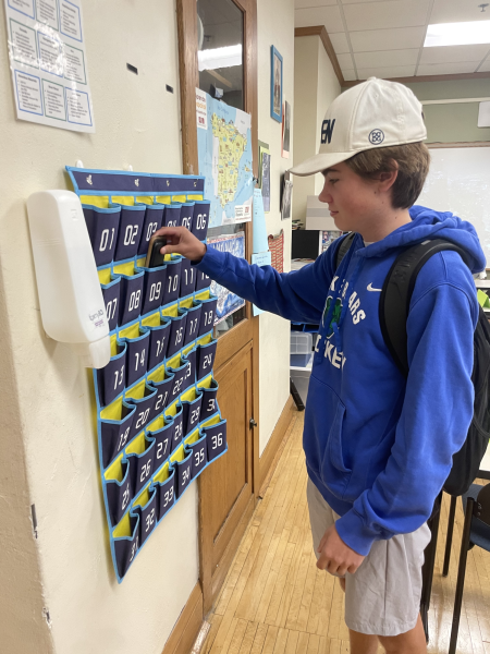 Jack Mark '26 places his phone in the cubbies before the start of Spanish class in Ms. Mateo's classroom.