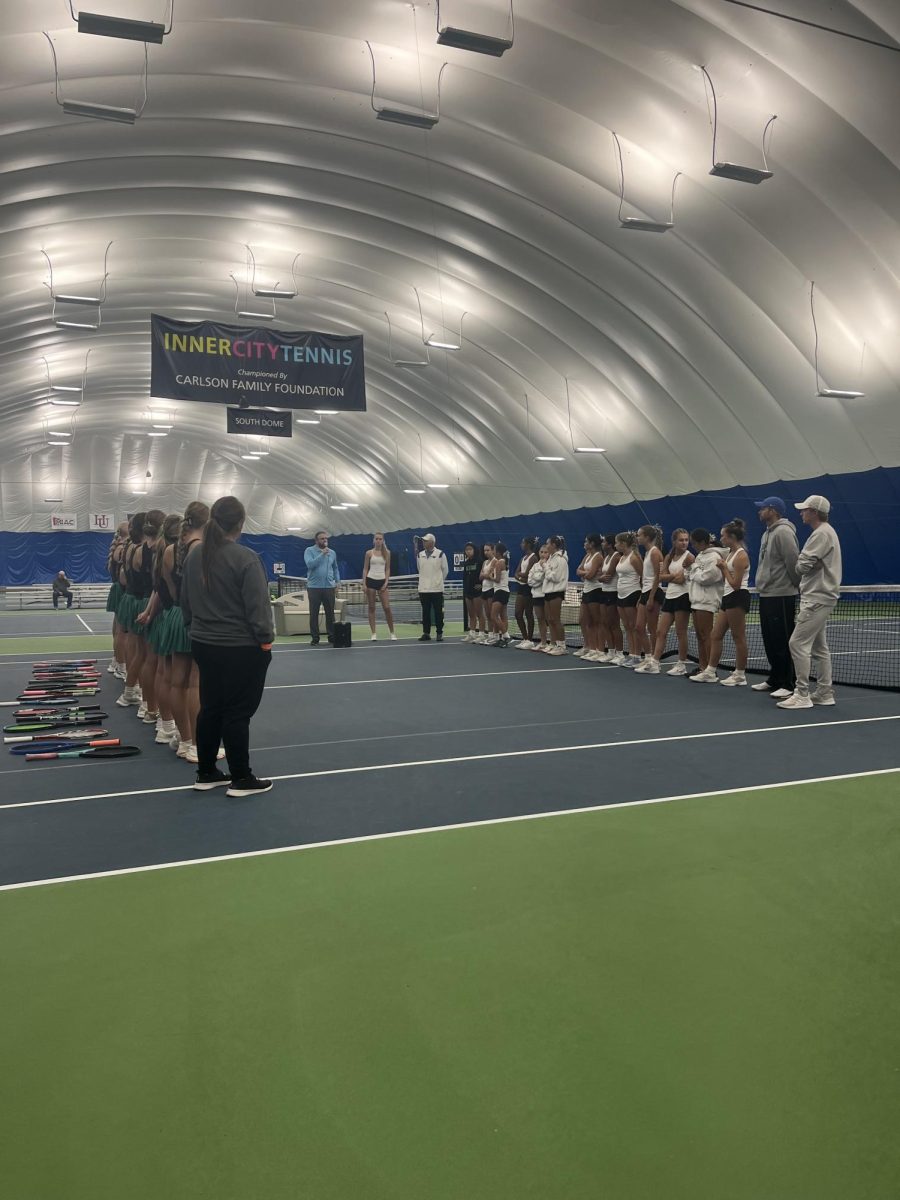 Girls' Tennis Team (white) lining up and meeting their opponent, Litchfield, in the Class A state tennis tournament championship at the InnerCity Tennis Center in Minneapolis. 